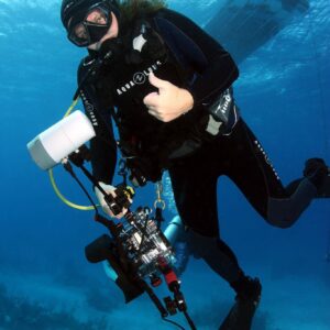 Photo of Andre Fedak under the sea holding underwater photography equipment.